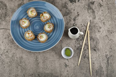 Mavi bir tabak soya soslu tempura rulo ve taş yüzeyinde wasabi. Yüksek kalite fotoğraf