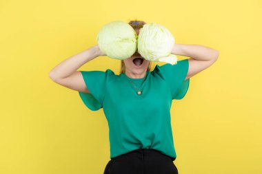 Sarı duvarın arkasında taze lahanaların arkasına saklanan genç ev kadınının görüntüsü. Yüksek kalite fotoğraf