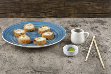 Mavi bir tabak soya soslu tempura rulo ve taş yüzeyinde wasabi. Yüksek kalite fotoğraf