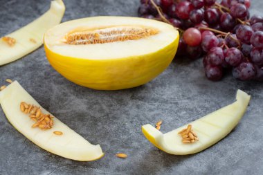 Taze kırmızı üzüm ve mermer zemin üzerinde sarı kavun kümesi. Yüksek kalite fotoğraf