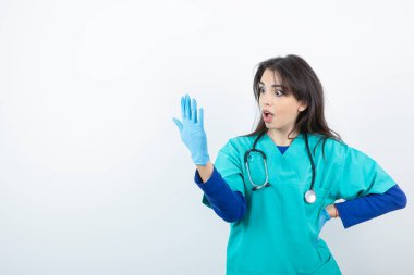 Tıp eldivenine bakan steteskoplu genç hemşire portresi. Yüksek kalite fotoğraf