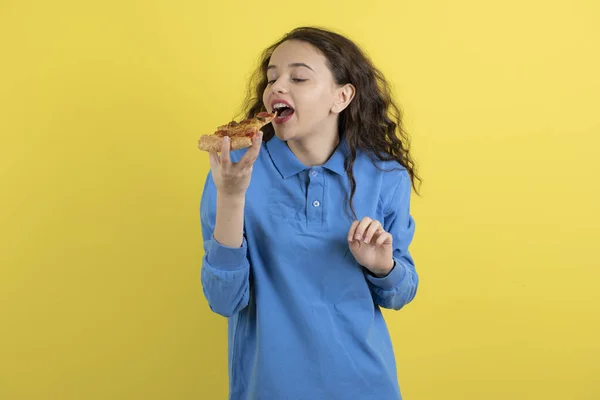 Fotografie Krásné Mladé Dívky Jíst Kus Pizzy Přes Žlutou Zeď — Stock fotografie