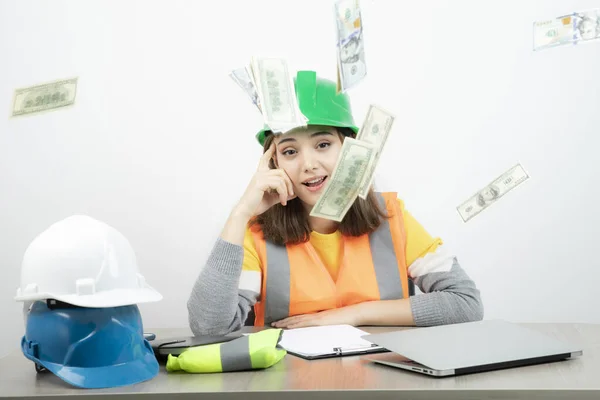 身穿橙色背心 头戴绿色头盔的女工坐在办公桌前 高质量的照片 — 图库照片