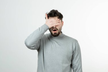 Yüzünü kaplayan gri kazaklı sakallı adamın portresi. Yüksek kalite fotoğraf