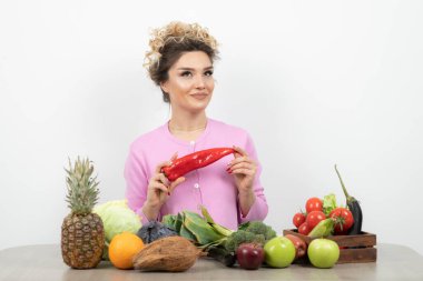 Masada çeşitli meyve ve sebzelerle poz veren güzel bir kadın.