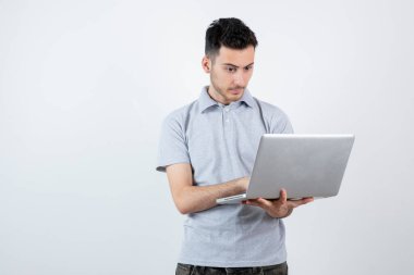 Bilgisayarı beyaz duvarın üstünde tutan genç adamın portresi. Yüksek kalite fotoğraf