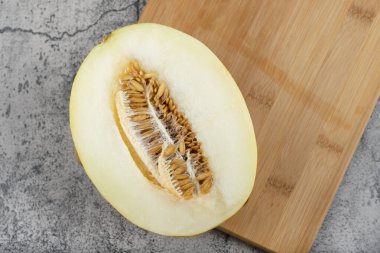 Tahta kesme tahtasına yarım dilimlenmiş sarı kavun yerleştirilmiş. Yüksek kalite fotoğraf