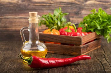 Tahta kutu dolusu taze dolma biber, zeytinyağı ve ahşap zemin üzerinde kırmızı biber. Yüksek kalite fotoğraf