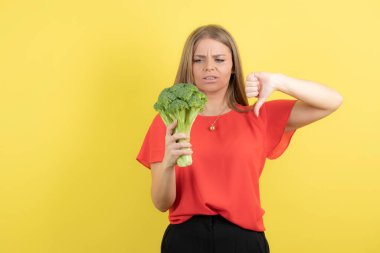 Büyük yeşil brokoli ile güzel bir kadın manken resmi baş parmağını aşağı gösteriyor. Yüksek kalite fotoğraf