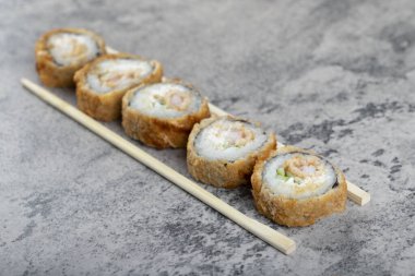 Sıcak kızarmış suşi ruloları ve taş masada tek kullanımlık tahta çubuklar. Yüksek kalite fotoğraf