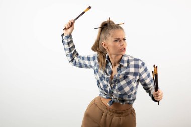 Beyaz bir duvarın üzerinde fırça tutan ve poz veren genç bir sanatçının portresi. Yüksek kalite fotoğraf