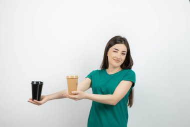 Mavi tişörtlü, elinde kahve tutan güzel bir kadının fotoğrafı. Yüksek kalite fotoğraf