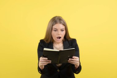 Resmi kıyafetli güzel bir kadın sarı arka plan notlarını kontrol ediyor. Yüksek kalite fotoğraf