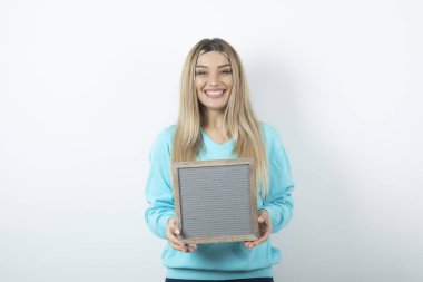 Beyaz duvara çerçeveyi dayamış güzel bir bayan portresi. Yüksek kalite fotoğraf