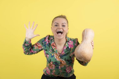 Sarı duvara taze tereyağlı kabak tutan bir kadın resmi. Yüksek kalite fotoğraf