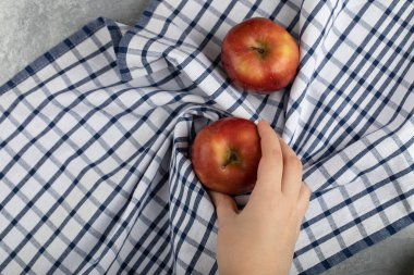 Masa örtüsünün üzerinde olgun kırmızı bir elmayı alan bir kadın eli. Yüksek kalite fotoğraf