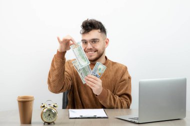 Genç ve mutlu muhasebeci masasında oturup paraları sayıyor. Yüksek kalite fotoğraf