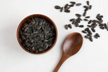 Tahta kase ve kaşık dolusu ayçiçeği tohumları beyaz arka plana yerleştirilmiş. Yüksek kalite fotoğraf