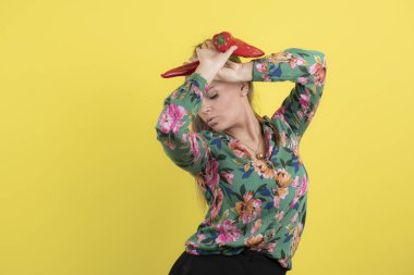 Sarı arka planda izole edilmiş iki kırmızı biberli poz veren güzel bir ev hanımı. Yüksek kalite fotoğraf