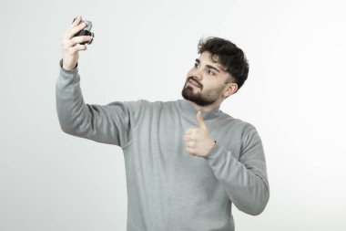Fotoğraf makinesiyle selfie çeken ve baş parmağını kaldıran yakışıklı bir adamın portresi. Yüksek kalite fotoğraf