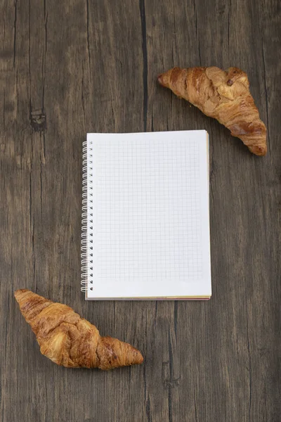 Sabrosos Croissants Mantecosos Con Cuaderno Blanco Colocado Mesa Madera Foto — Foto de Stock