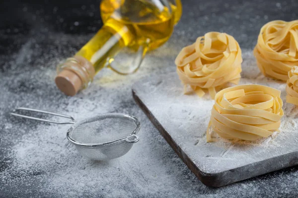 Tahta ahşap tagliatelle tahtasının üzerinde un ve zeytinyağı olan yuvaları var. Yüksek kalite fotoğraf