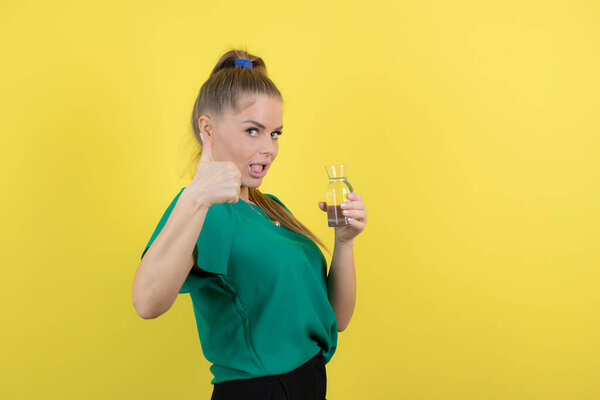Beautiful woman in casual outfit holding glass of water and giving thumbs up. High quality photo