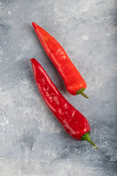 Mermer zemin üzerine iki kırmızı biber yerleştirilmiş. Yüksek kalite fotoğraf
