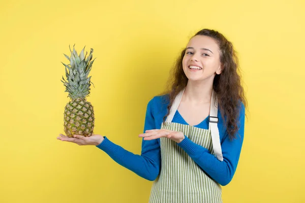 Młoda Nastolatka Fartuchu Trzymająca Dojrzały Ananas Żółtej Ścianie Wysokiej Jakości — Zdjęcie stockowe