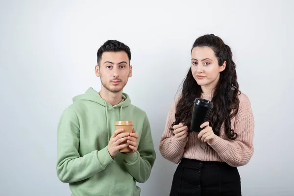 白い壁にコーヒーを飲みながら立っている若いカップル 高品質の写真 — ストック写真
