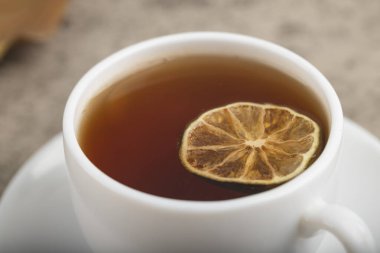 White cup of black tea with lemon slice on stone background. High quality photo