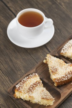 Hindistan cevizi dilimli tatlı dilimleri ve ahşap masaya konmuş bir fincan çay. Yüksek kalite fotoğraf