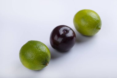 Taze yeşil limon ve beyaz arka planda izole edilmiş mor erikler. Yüksek kalite fotoğraf