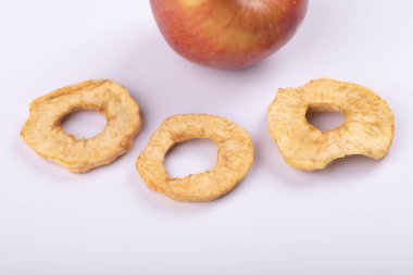 Beyaz yüzeyde kırmızı taze elma ve kurutulmuş elma halkaları. Yüksek kalite fotoğraf