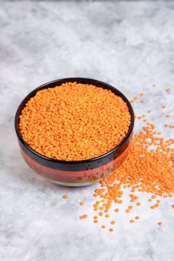 Mermer arka planda bir kase dolusu çiğ kırmızı mercimek çekirdeği. Yüksek kalite fotoğraf