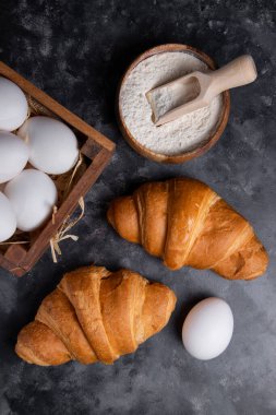 Tavuk yumurtalı taze kruvasan ve ahşap un kasesi. Yüksek kalite fotoğraf