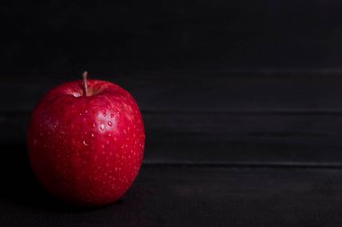 Su damlalarındaki kırmızı elma koyu ahşap bir masaya konur. Yüksek kalite fotoğraf