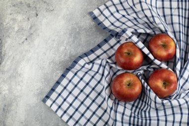 Mermer zemin üzerinde çizgili masa örtüsü olan lezzetli kırmızı elmalar. Yüksek kalite fotoğraf