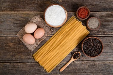 Çiğ spagetti, yumurta ve ahşap yüzeye yerleştirilmiş bir kase biber. Yüksek kalite fotoğraf
