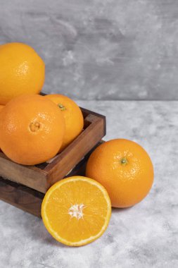 Mermer zemin üzerine yerleştirilmiş içi tamamen kesilmiş portakal meyveleriyle dolu ahşap bir kutu. Yüksek kalite fotoğraf
