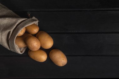 Siyah yüzeydeki eski çuval bezinden taze patates yığını. Yüksek kalite fotoğraf