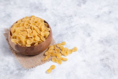 Tahta kase dolusu çiğ Farfalle makarnası mermer masaya yerleştirilmiş. Yüksek kalite fotoğraf