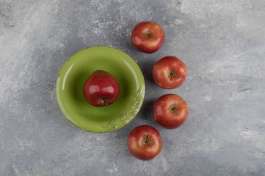 Mermer yüzeyinde tek kırmızı elma olan yeşil kase. Yüksek kalite fotoğraf