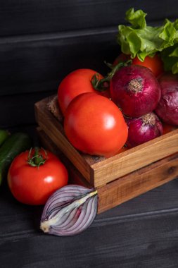 Koyu ahşap bir masanın üzerine taze olgun sebzelerle dolu ahşap bir kutu. Yüksek kalite fotoğraf
