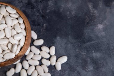 Kuru fasulye dolu ahşap bir kase taştan bir arka fona yerleştirilmiş. Yüksek kalite fotoğraf