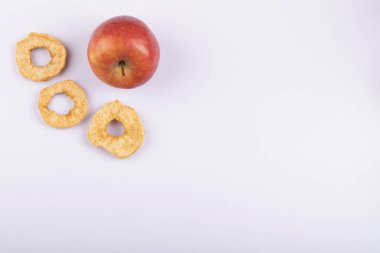Beyaz yüzeyde kırmızı taze elma ve kurutulmuş elma halkaları. Yüksek kalite fotoğraf