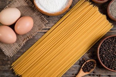 Çiğ spagetti, yumurta ve ahşap yüzeye yerleştirilmiş bir kase biber. Yüksek kalite fotoğraf