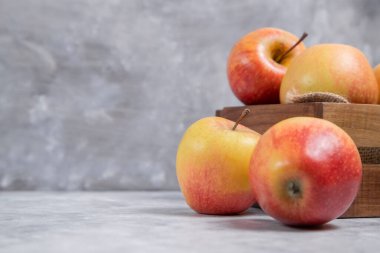 Mermer bir arka fona yerleştirilmiş taze kırmızı elma meyveleriyle dolu ahşap bir kutu. Yüksek kalite fotoğraf