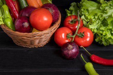 Taze olgun sebzelerle dolu bir hasır sepet. Koyu ahşap bir masanın üzerine yerleştirilmiş. Yüksek kalite fotoğraf