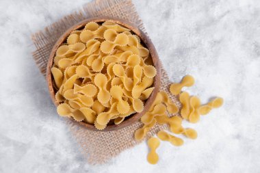 Tahta kase dolusu çiğ Farfalle makarnası mermer masaya yerleştirilmiş. Yüksek kalite fotoğraf